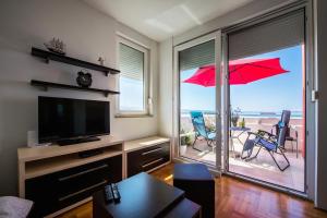 a living room with a television and a patio with an umbrella at Apartment Dominik in Podstrana