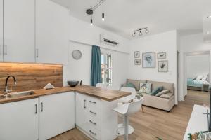 a kitchen with white cabinets and a living room at ΙΖΑΜΠΩ II in Kalamata