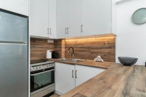 a kitchen with white cabinets and a wooden counter top at ΙΖΑΜΠΩ II in Kalamata +17 photos