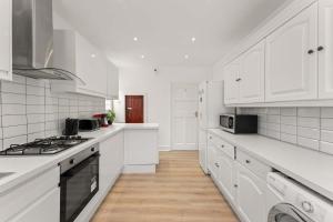 eine weiße Küche mit weißen Arbeitsflächen und weißen Schränken in der Unterkunft Stylish 5 Bed Home in Forest Hill by Amber Stays, Perfect for Business & Contractors Sleeps 16 in Forest Hill