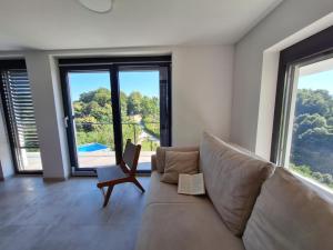 a living room with a couch and a chair and windows at En hribček in Ptujska Gora