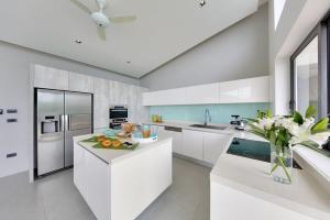 una cocina con armarios blancos y un jarrón de fruta en una barra en Maeva Villa Koh Samui, en Nathon Bay