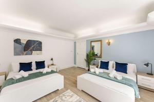 2 Betten in einem weißen Zimmer mit blauen Kissen in der Unterkunft Stylish 5 Bed Home in Forest Hill by Amber Stays, Perfect for Business & Contractors Sleeps 16 in Forest Hill