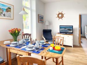 a dining room with a table and chairs and a television at Fewo Anker in der Villa Victoria in Graal