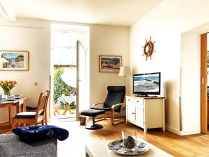 a living room with a tv and a table and chairs at Fewo Anker in der Villa Victoria in Graal +19 photos