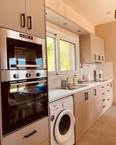 a kitchen with a stove and a washer and dryer at Villa Banana in Lourdata