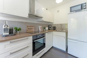 a kitchen with white cabinets and black appliances at Fehmarnwelle in Niendorf +23 photos