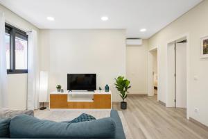 a living room with a blue couch and a tv at Coração da Madeira by Homie in Curral das Freiras