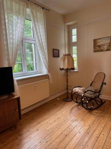 a living room with a chair and a lamp and two windows at Landhausvilla Gut Vogelsang in Lalendorf