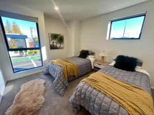 a bedroom with two beds and a large window at Luxury corner 2BR Townhouse with parking in Christchurch