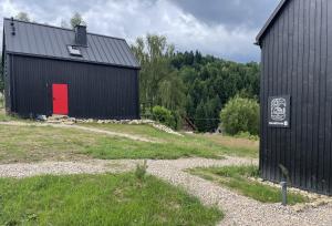 a black barn with a red door in a field at BeskiDom in Zawoja