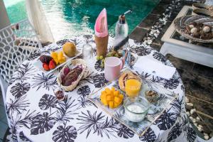 a table with fruit and drinks on a table with the water at Chambres d'hôtes & spa Le Jardin de Ravintsara in Ravine des Cabris