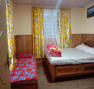 a bedroom with two beds and a window with curtains at Nawang Homestay By StayApart in Takdāh