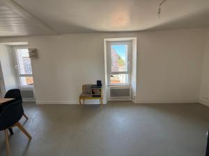 an empty room with a chair and two windows at Appartement meublé T2 PONT REAN - Centre in Guichen