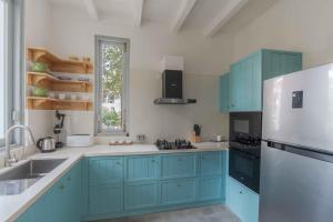 a kitchen with blue cabinets and a white refrigerator at Villa Mandarina by The Blue Kite - 4BHK Standalone Luxuxy Villa in Assagao with Large Private Pool, Pool Table, Kids Play Area, Garden, Caretaker & Security in Siolim