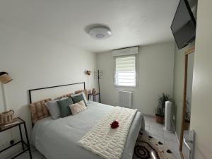 a bedroom with a white bed with a red flower on it at Suite Eden Spa, Appart'hôtel bien être , Patio de standing barbecue - TV XL CinéSport, Lit Q-Size, Wifi, P-Gratuit en Résidence in Avion +30 photos