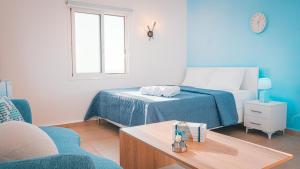 a blue and white bedroom with a bed and a table at Arka - Studio B in Anfah