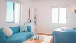 a living room with a blue couch and two windows at Arka - Studio B in Anfah