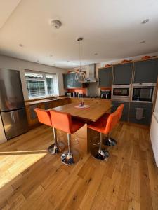een keuken met een houten tafel en oranje stoelen bij Home at Number 27 in Trowbridge