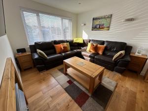 a living room with a leather couch and a coffee table at Home at Number 27 in Trowbridge