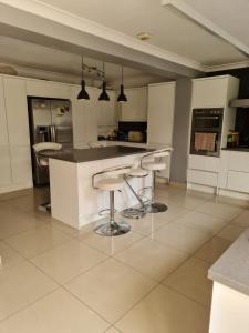 a kitchen with white cabinets and bar stools at Room Four in Earley