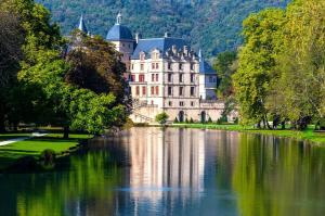 a large castle sitting on the side of a lake at Appartement La veg'it in Seyssins