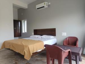 a bedroom with a bed and a desk and a chair at HimaViswa Farmstay in Hospet