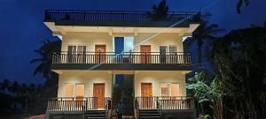 a large white building with a balcony at night at HimaViswa Farmstay in Hospet