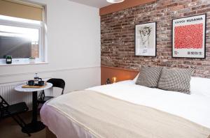 a bedroom with a brick wall and a bed and a table at Settle in Southampton - Stylish Self Check-In Rooms & Suites in Southampton +94 photos