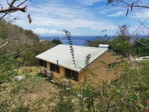 a yellow house with a white roof on a hill at KaZandoli in Les Anses-dʼArlets