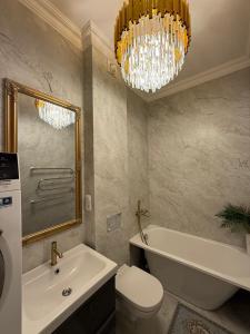 bagno con lavabo, servizi igienici e lampadario pendente. di Centre GRANT Apartment a Klaipėda