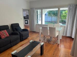 a living room with a couch and a table and chairs at Central Spacious House With Backyard And Patio in Palmerston North