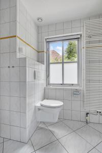 a white bathroom with a toilet and a window at Vakantiewoning Woudzicht - Stijlvol genieten in Nijkerk