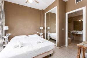 ein Schlafzimmer mit einem großen weißen Bett und ein Badezimmer in der Unterkunft Campomanes Luxury Terrace Apartment in Alicante