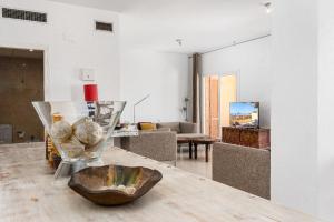 eine Vase mit Muscheln auf einem Holztisch in einem Wohnzimmer in der Unterkunft Campomanes Luxury Terrace Apartment in Alicante