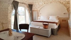 a bedroom with a bed and a table and a desk at I Trulletti del Gelso a Masseria Santalachicca in Masseria Orimini