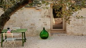 a green table and a vase next to a building at I Trulletti del Gelso a Masseria Santalachicca in Masseria Orimini