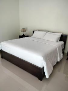 una cama grande con sábanas y almohadas blancas en Jepun Bali Villa, en Temukus