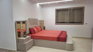 a bedroom with a bed with red sheets and a window at Luxe Suite au sein d'une villa in Rabat
