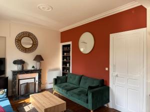 a living room with a green couch and a fireplace at L'AUTHENTIQUE in Saint-Brieuc