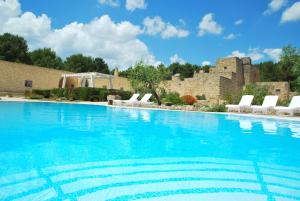 a large swimming pool with white chairs and a building at Masseria Relais Santa Teresa in Sannicola