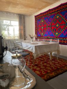 a dining room with a table and a colorful wall at Nomad place - horse riding tour Son-Kul in Dzhangyaryk