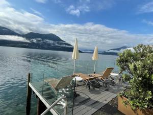 a deck with chairs and umbrellas on the water at Ferienwohnung Brissago in Brissago