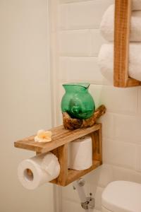 a green glass vase on a wooden shelf in a bathroom at Tropical Kasbah Ubud Central - Private Studio Rooms in Ubud