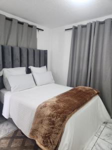 a bedroom with a large white bed with gray curtains at Hayley's inn at village blues in Johannesburg