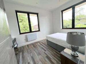 a bedroom with a bed and two windows at MK WhiteHouse cottage in Milton Keynes