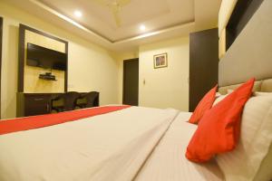 a bedroom with a white bed with orange pillows at Collection O Tip Top in Jaipur