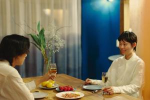 two women sitting at a table with glasses of wine at まちの別邸 緝 shu in Kochi