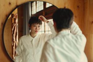 a woman brushing her hair in front of a mirror at まちの別邸 緝 shu in Kochi