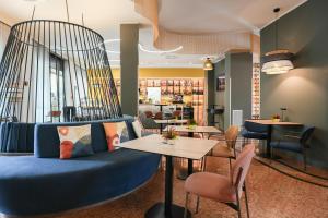a lobby with a blue couch and tables and chairs at Mercure Bologna Centro in Bologna